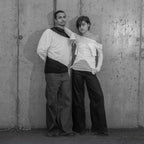 Two people posing against a textured wall.